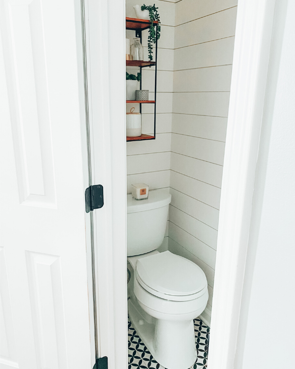 The same grout color as the tiles and white shiplap make this small half bathroom look larger.
