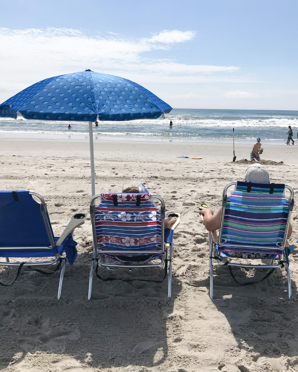 Sitting in beach chairs under an umbrella