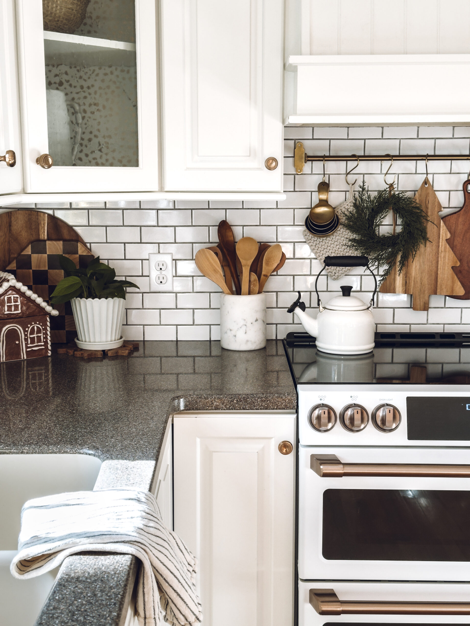 a hook rack above the stove with item hanging on the hooks like cutting boards and a mini wreath